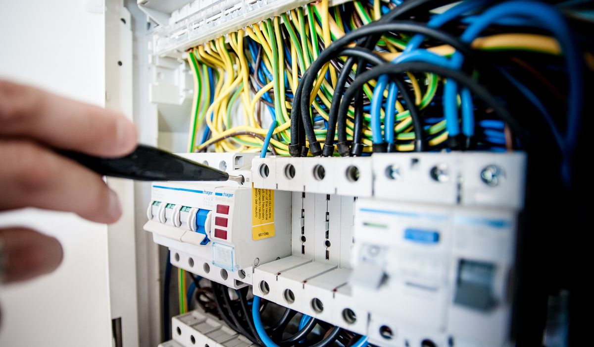 Electrician's hand working on breakers in a distribution board