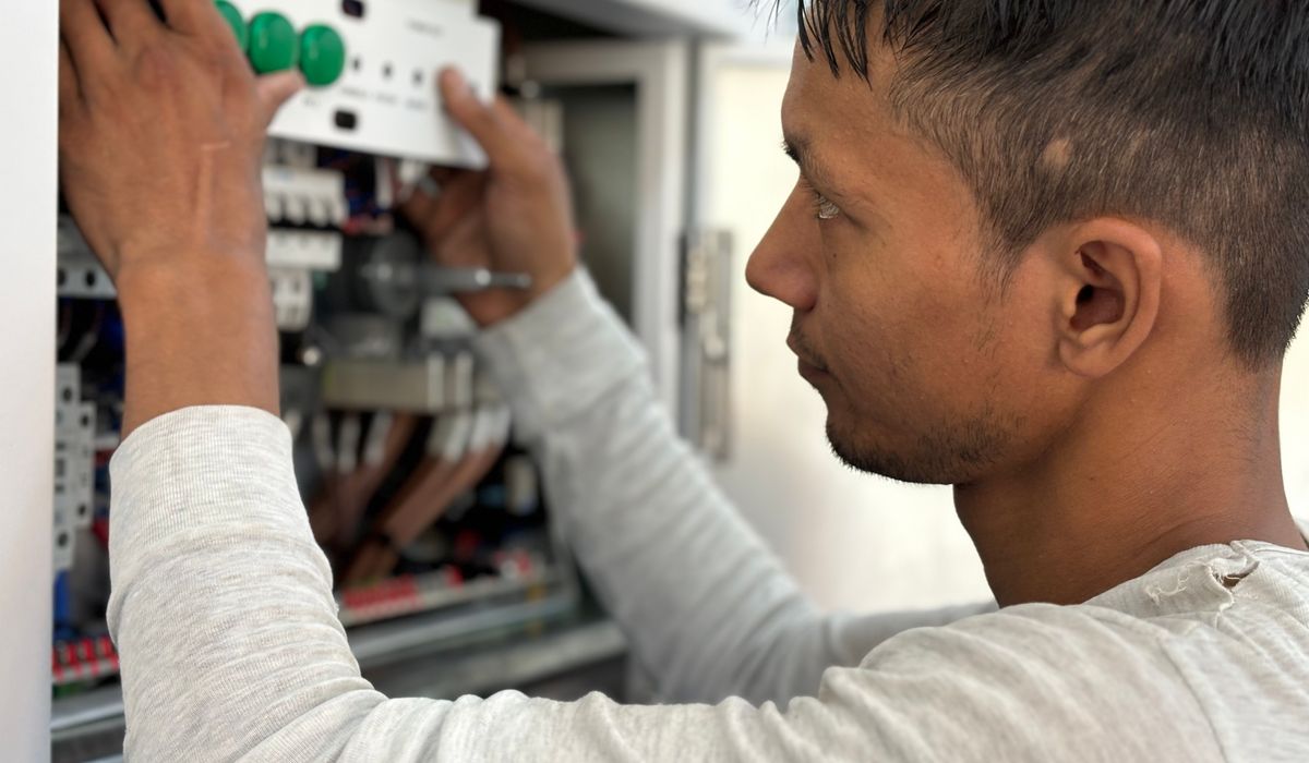 Technician fitting a cover onto an electrical control panel